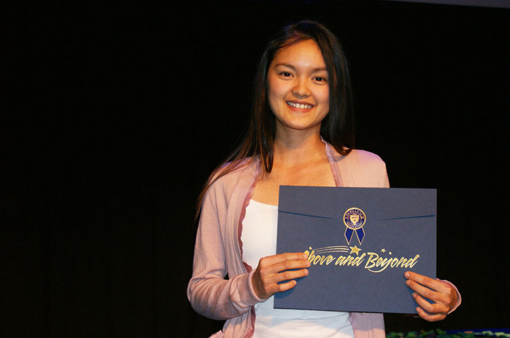 Student holding up an elegant envelope bearing the words "Above and Beyond"
